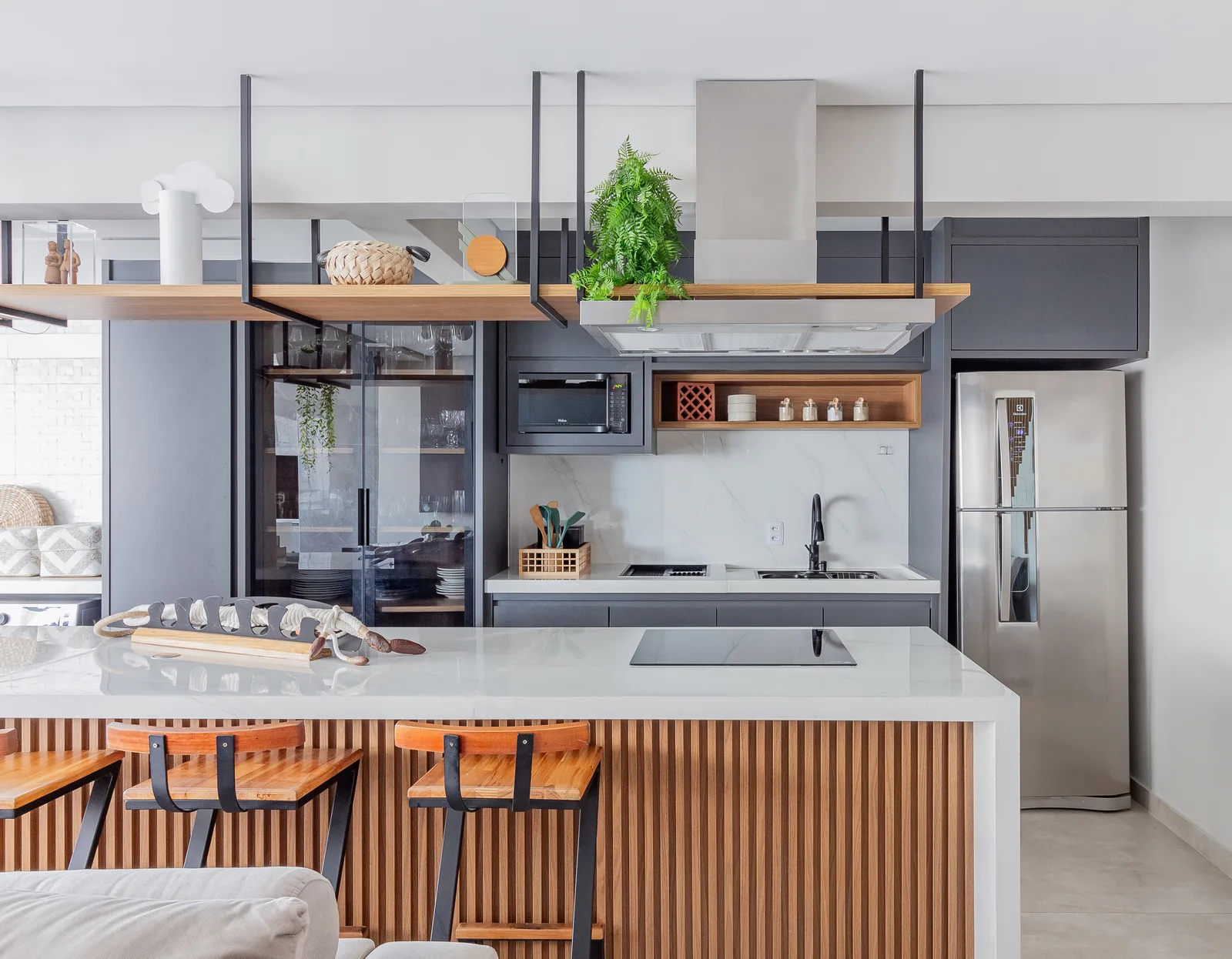 Cozinha integrada à sala, com ilha ripada e cooktop na bancada