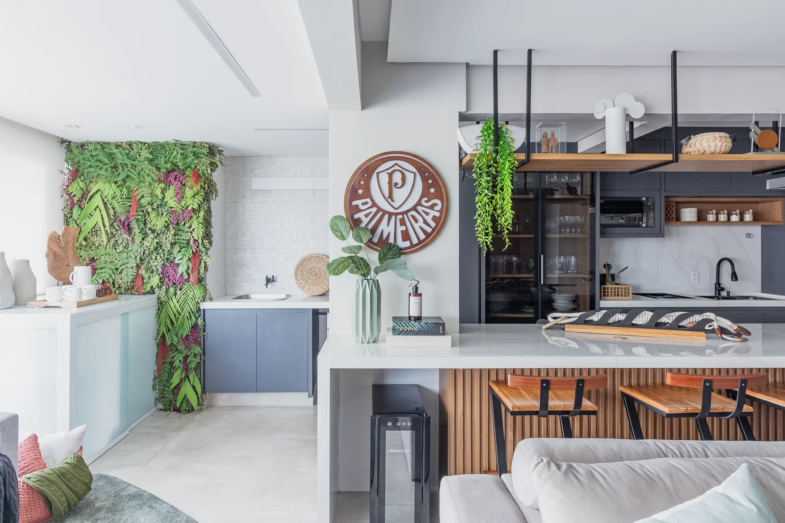 Sala integrada à cozinha, com jardim vertical e bancada de apoio