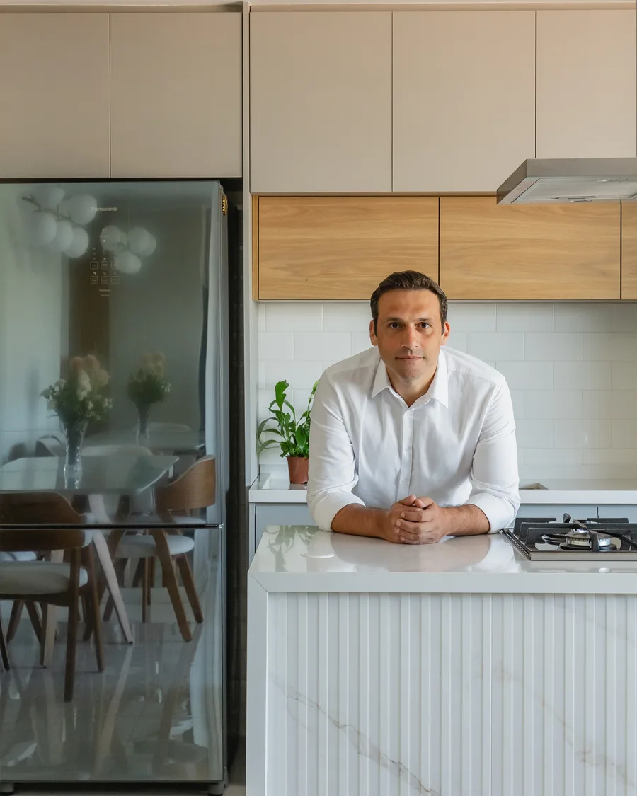 Adriano Medeiros apoiado na ilha de uma cozinha entregue pelo escritório